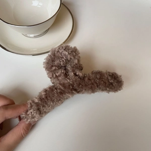 Détail d'une grande pince à cheveux en peluche marron avec texture douce en laine d'agneau