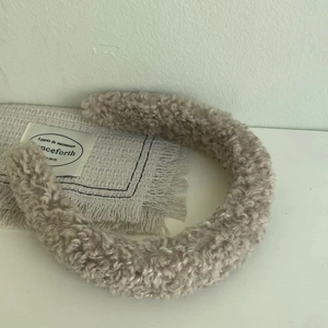 Detail of soft beige teddy fleece headband on decorative fabric with vintage card