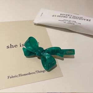 French handmade green marble acetate bow hair clip on a minimalist cream background