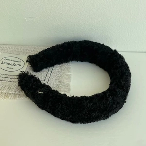 Detailed view of black fuzzy teddy fleece headband with soft curly wool texture