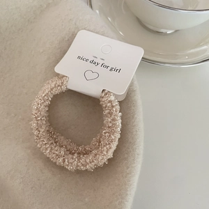 Detail of soft beige sherpa scrunchie on fabric with a cozy decorative ceramic teacup