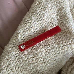 Red acetate hair clip with heart rhinestone and gold handmade lettering on knit background
