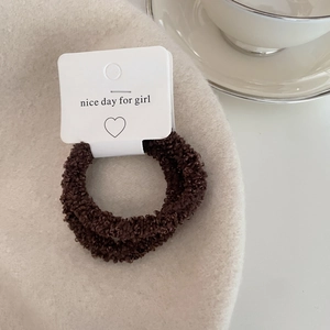 Close-up of coffee brown plush hair scrunchie set on beige beret and white tea set