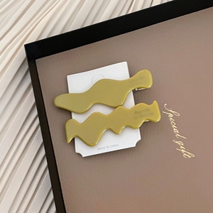 Détail de pinces à cheveux ondulées en acétate français vert olive avec clips métalliques