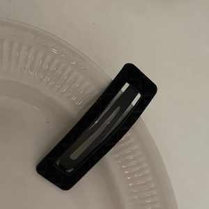 Detail view of a black hollow rectangular hair clip with a stylish diamond grid texture