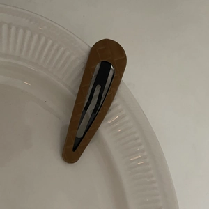 Brown checkered pattern faux leather water drop hair clip on a white decorative plate