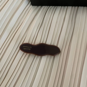 Detailed macro view of wavy dark brown tortoiseshell acetate hair clip with gold text