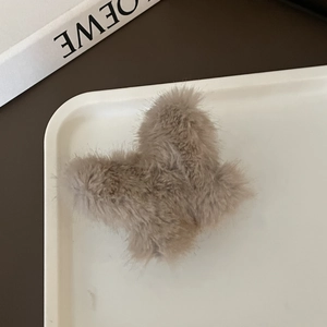 Primer plano de una pinza para el cabello de mariposa de felpa marrón en bandeja blanca