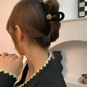 Detail of velvet black hair claw with gold camellia flower for French style updo