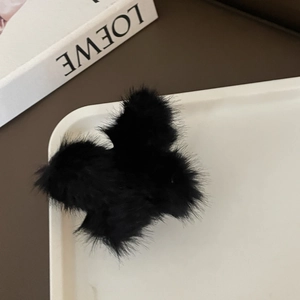 Primer plano de pinza para el pelo de piel sintética negra sobre bandeja blanca
