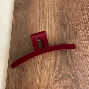 Macro detail of wine red flocked finish on a large claw clip with metal spring