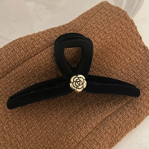 Vintage black velvet hair claw clip with golden camellia flower accent on brown fabric