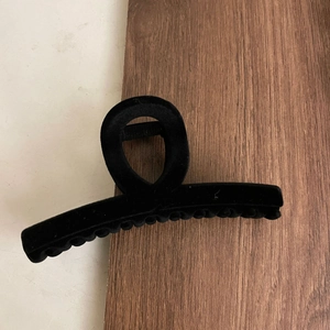 Macro detail of large black flocked cross hair claw clip with a velvet texture finish
