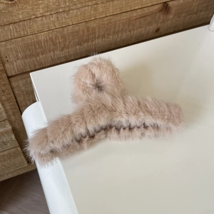 Macro detail of plush faux rabbit fur hair claw clip in a soft nude pink finish