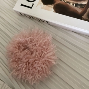 Détail d'un chouchou rose en fausse laine avec texture moelleuse sur tissu rayé