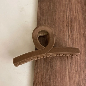 Detail of oversized dark brown flocked hair claw clip with velvet texture and metal spring