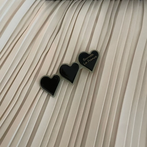 Macro detail of black heart hair clip with gold Barrette La France text on pleated fabric