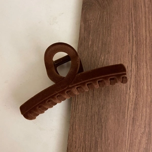 Close-up of deep brown flocked hair claw clip with twisted matte velvet texture