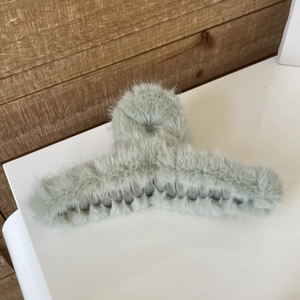 Close-up of sage green faux fur large shark hair claw clip with plush texture detail