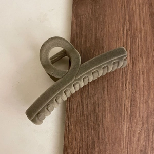 Macro shot of large olive green flocked hair claw clip with crossed teeth design