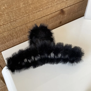 Detail of oversized black faux rabbit fur shark hair claw clip with long dense plush texture