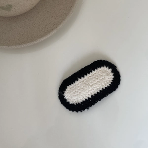 Detailed view of handmade crochet bow hair clip with textured beige and black knit
