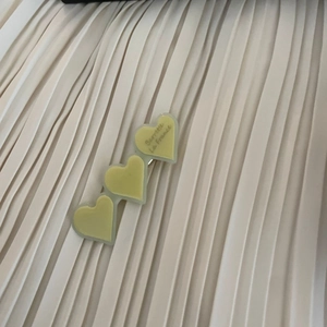 Detail of three acetate heart hair clips with Barrette La France text on fabric