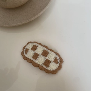 Close-up of handmade checkerboard knit hair clip with crochet lace trim edges
