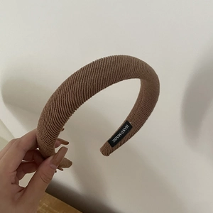Detailed close-up of brown knitted sponge headband with a black handmade label inside