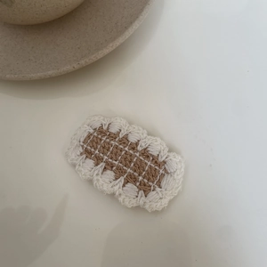 Detailed macro of handmade crochet hair clip with a stylish beige checkered pattern