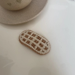 Macro view of a hand-woven beige and brown checkered bow hairclip for children