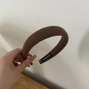 Detail of brown ribbed sponge headband featuring an interior handmade woven label