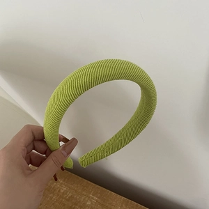 Close-up of a bright green ribbed sponge headband for women with a puffy design