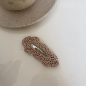 Detailed macro of hand-knitted brown cloud-shaped hair clip with soft cotton texture