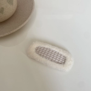 Detailed view of beige faux fur hair clip with grey and white checkered fabric pattern