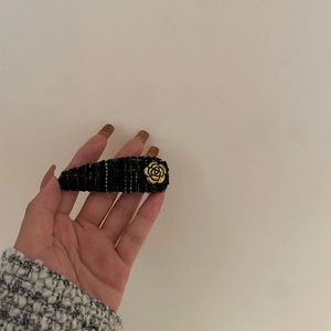 Close-up of a vintage black tweed hair clip with a gold camellia flower embellishment