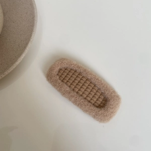 Detailed close-up of a plush beige checkered hair clip for kids with soft furry texture