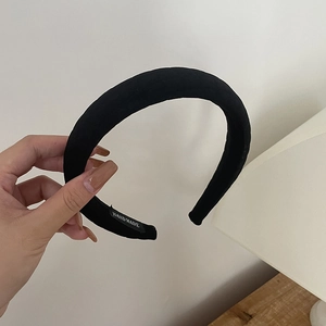 Detailed view of handmade black padded headband with fabric texture and interior woven label