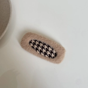 Close-up of checkered plush hair clip for girls with soft faux fur trim and warm brown tones
