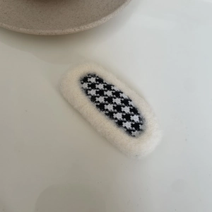 Close-up of elegant houndstooth fabric hair clip with soft white plush trim details