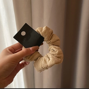 Quilted beige scrunchie for women made of textured fabric with a minimalist design