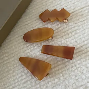 Set of four geometric amber acetate hair clips on soft white fleece background