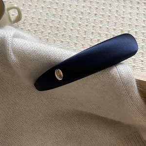 Detailed view of deep blue satin headband with a gold emblem on knit fabric