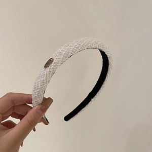 Detail of white tweed headband with gold metal accent and non-slip black velvet lining