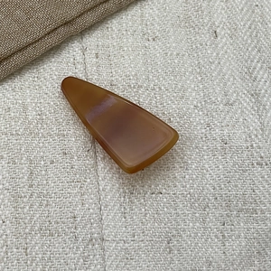 Amber geometric acetate triangle hair clip with retro tortoise shell pattern on beige fabric