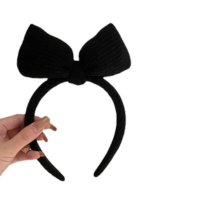 Knitted black oversized bow headband for women featuring a textured ribbed fabric finish