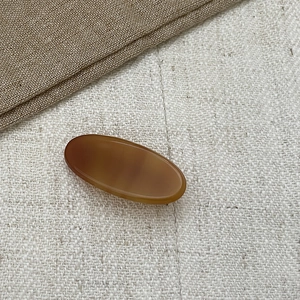 Close-up of an oval tortoiseshell acetate hair clip with a polished amber finish