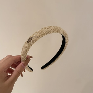 Detail of beige tweed headband with gold metal buckle and elegant woven texture