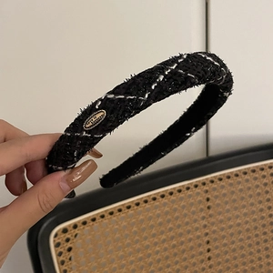 Close-up of black tweed headband with gold metal plate engraved with Love is Forever
