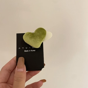 Detail einer herzförmigen Haarklammer mit avocadogrüner Samttextur auf Karte